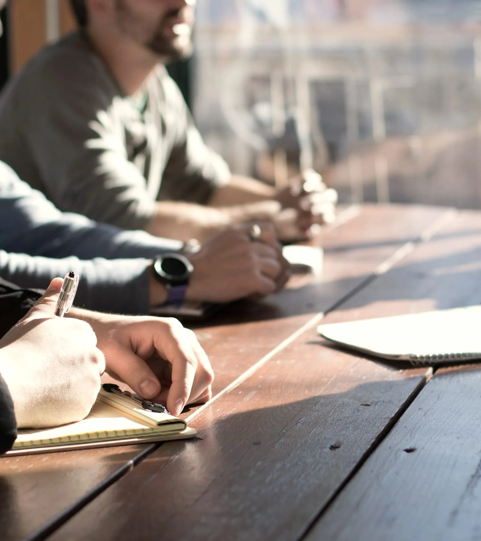 Two people talking across a table, one of them taking notes